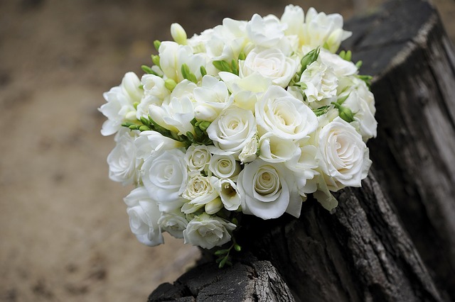Overhead shot of an abundant bridal bouquet with garden roses dahlias and trailing foliage on a marble surface